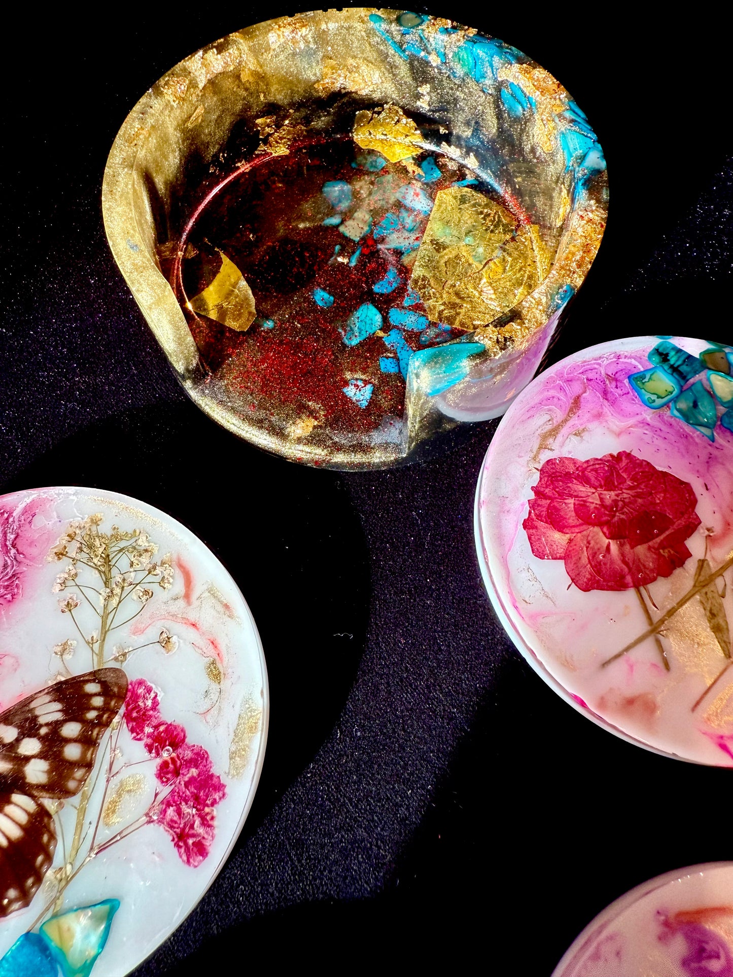 Decorative items with floral and butterfly designs on a dark background