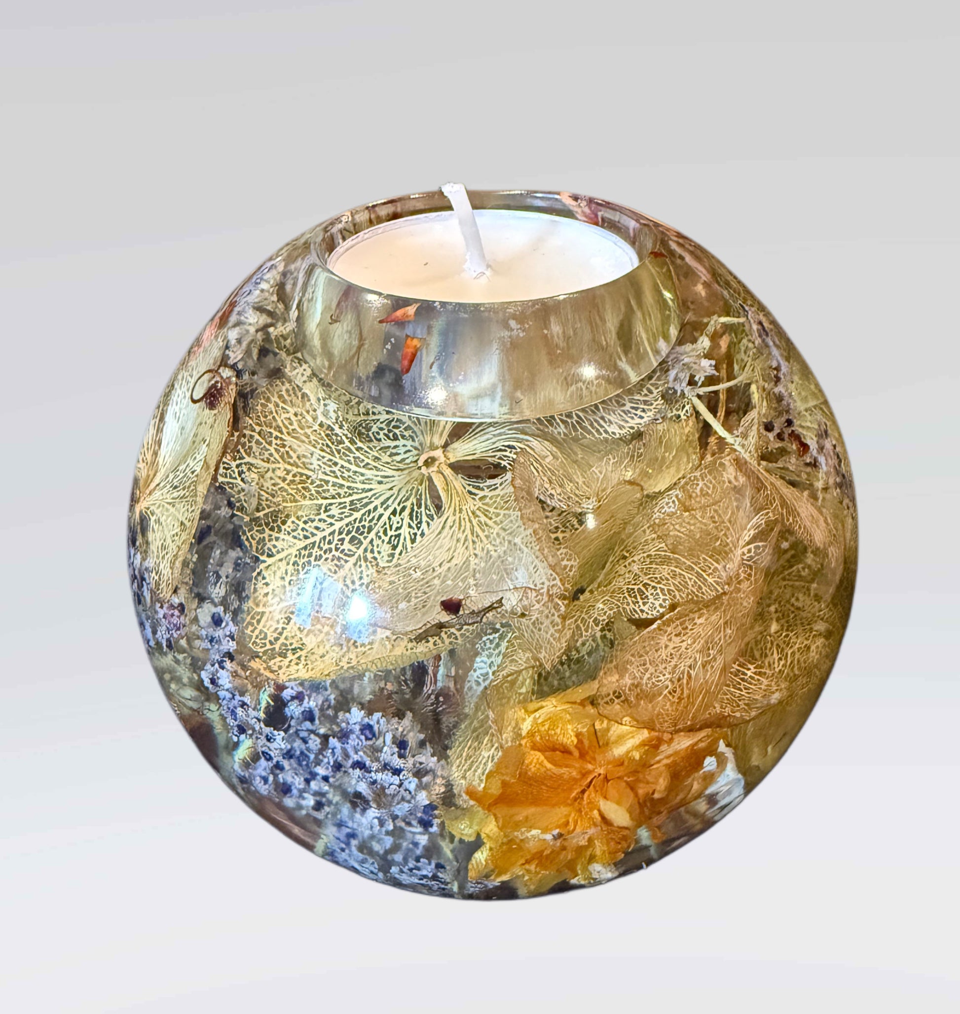 Decorative candle holder with floral and leaf patterns on a white background